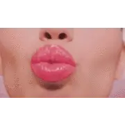 Close-up of glossy pink lips blowing a kiss