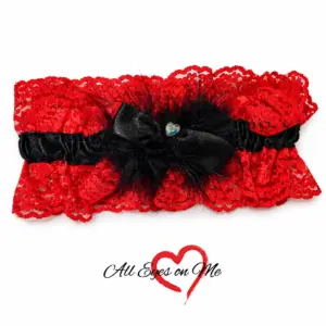 Red lace garter with black satin band, black feather trim, bow and heart detail, front view