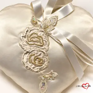 Off-white satin heart ring cushion with two beaded lace flowers, sequinned leaves and satin ribbon loops.
