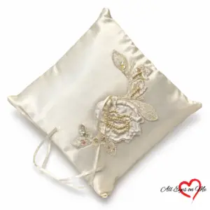 Off-white satin ring cushion with a beaded floral appliqué, sequinned leaves and ribbon ties