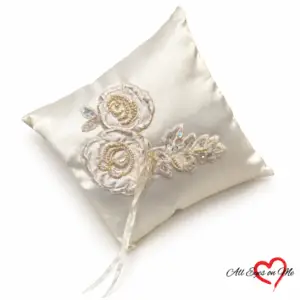 Off-white satin ring cushion with two beaded floral appliqués, sequinned leaves and ribbon ties