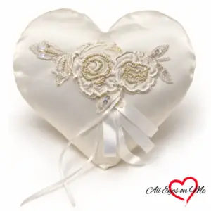 Off-white heart-shaped ring cushion with two beaded lace flowers, sequinned leaves and satin ribbons