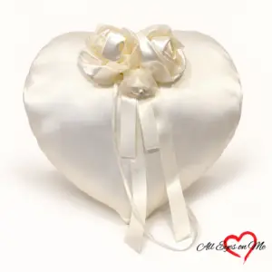 Off-white heart-shaped satin ring cushion with three fabric roses and ribbon ties.